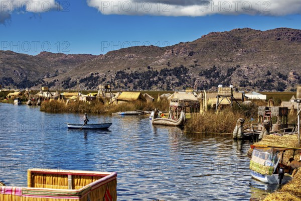 Canoe on a lake with traditionally built reed huts and mountains, The floating reed islands of the