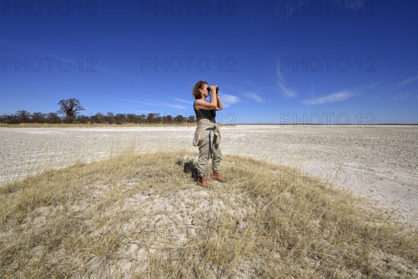 Tourist observes animals through binoculars near the Baines Baobabs, Kudiakam Pan, Nxai-Pan
