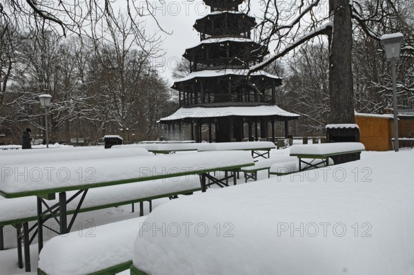 Winter in the English Garden, snow-covered beer garden tables and benches, Chinese Tower, Munich,