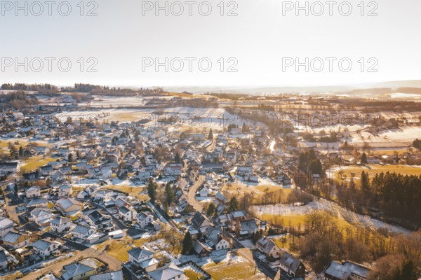 A wintry hilly landscape with a village under snow-covered roofs, surrounded by fields, Hallwangen,