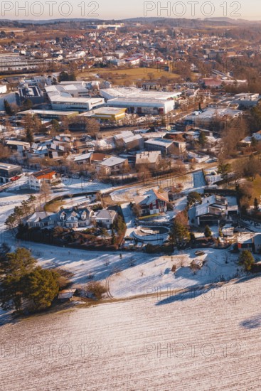 Wintery city view with snow-covered houses and trees in soft orange tones, Hallwangen, Freudenstadt