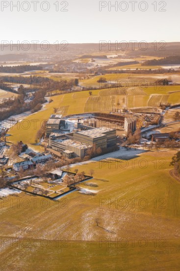 Wintery field landscape with industrial buildings in the distance under clear skies, Hallwangen,