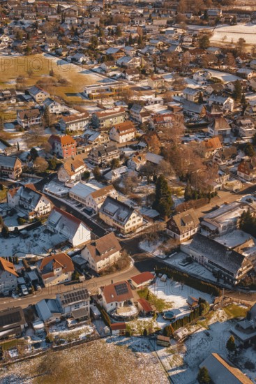 Bird's-eye view of city with snow-covered roofs in winter at sunset, Hallwangen, Freudenstadt