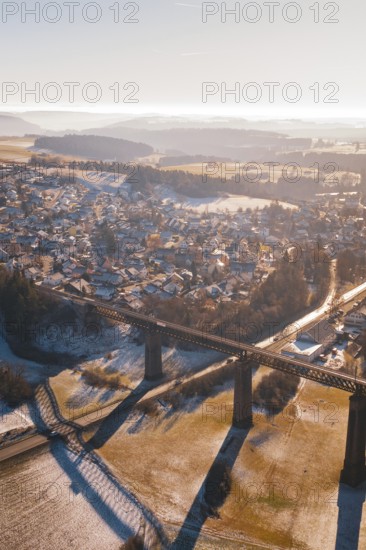 Aerial view of a snowy village and bridge with a wide view over the countryside, Aach, Dornstetten,
