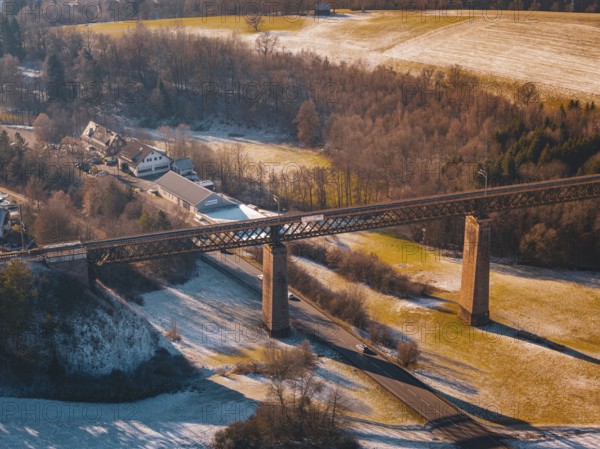 Bridge spanning a snowy valley next to a village under mild sunlight, Aach, Dornstetten,