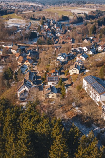 Aerial view of a snowy village with numerous roofs and surrounding forest, Aach, Dornstetten,