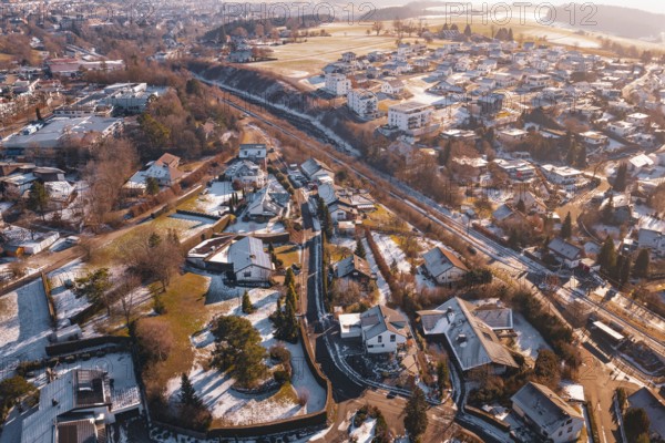 Village area with residential buildings under a light layer of snow in the morning sun,