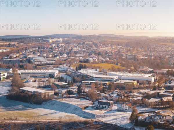 City view in winter with snow-covered fields and buildings under a foggy sky, Dornstetten,