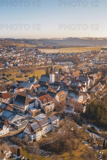 Aerial view of a town with church in the center, surrounded by buildings and winter landscape under