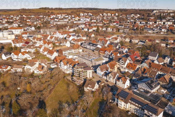 Aerial view of a city with many buildings and red roofs, in a wintry landscape in sunshine,