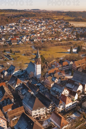 Aerial view focusing on church surrounded by city buildings in a wintry environment in sunlight,