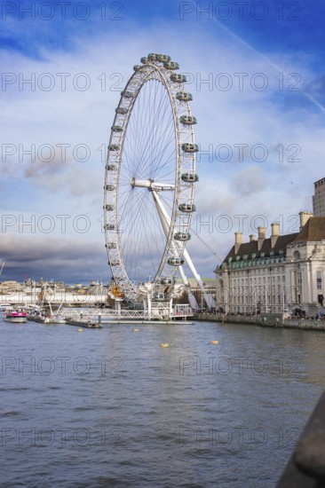 City view with Ferris wheel and river under cloudy sky, London Eye, London, United Kingdom