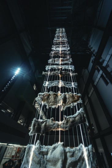 Tall vertical installation with metal and fur elements in a dark room, Tate Modern of Art, Lodon,