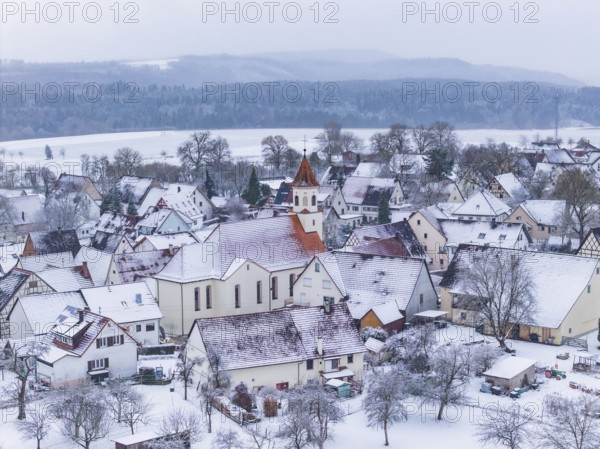 Snowy village landscape in winter, dominating church surrounded by trees, Wiesenstetten,