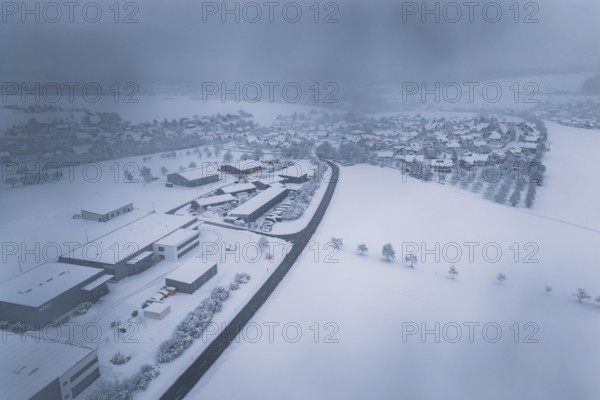 Wintery snowy village with buildings and roads under a thick blanket of fog, Hörschweiler,