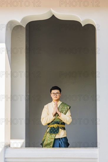 Young man in traditional clothing presenting himself to photographers, Wat Arun Buddhist temple,