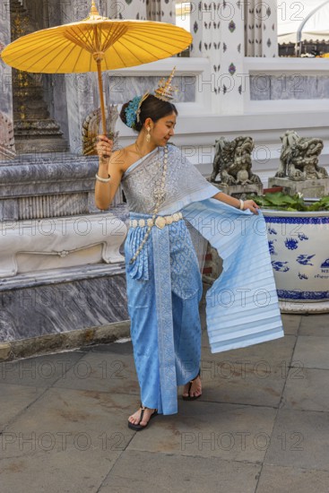 Young woman wearing a parasol in traditional clothing presents herself for the photographers, Wat