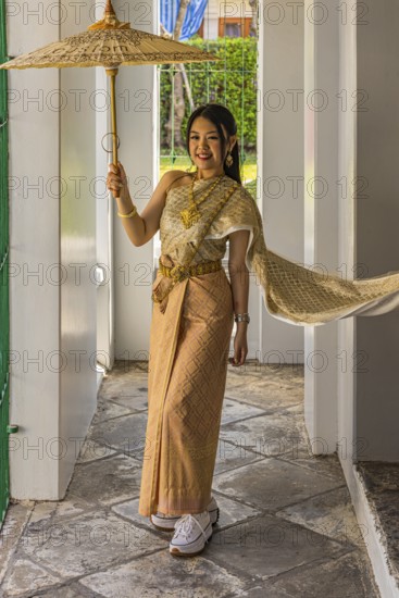 Young woman wearing a parasol in traditional clothing presents herself for the photographers, Wat