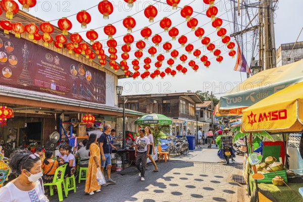 Busy access road covered with red lanterns, to Wat Arun Buddhist temple, Bangkok, metropolis of