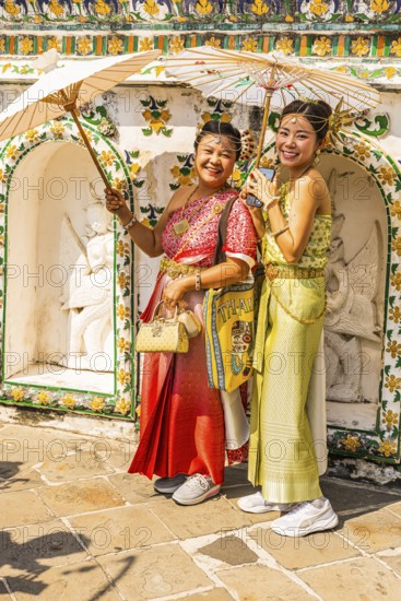 Young woman with umbrellas in traditional clothing present themselves for the photographers, Wat