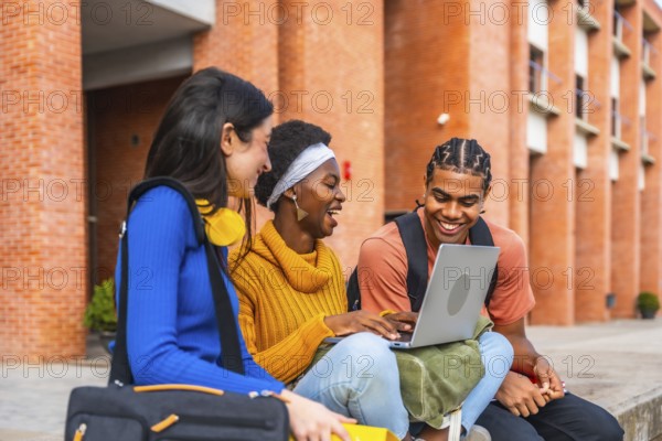 Group of diverse university students smiling and interacting outdoors, using a laptop, representing