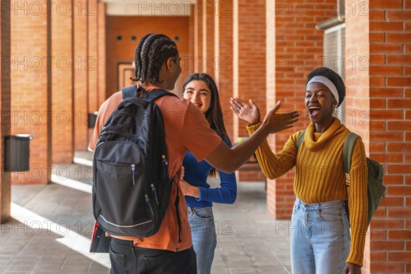 Diverse young students are happily greeting each other while walking along a brick wall corridor on