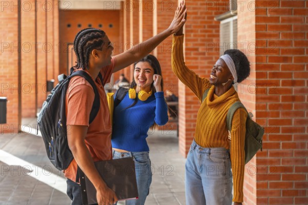 Diverse university students high fiving outdoors, celebrating teamwork and friendship on campus,