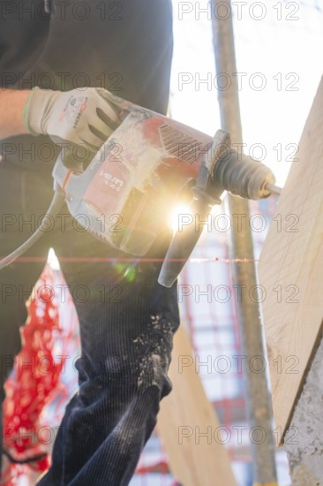 Drilling work in sunlight on construction site with wooden elements, carpentry construction, roof