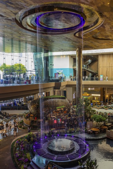Artificial, brightly lit waterfall, magic waterfall, plunging from ceiling into a water basin,