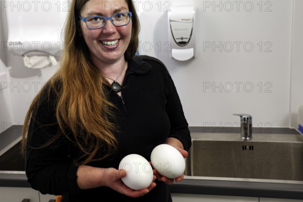 Woman smiles while holding two kiwi eggs in her hands, Rotorua, Bay of Plenty, New Zealand