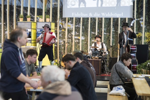 Visitors and the band Fidelius & die Waldvögel at the Green Week on the exhibition grounds in