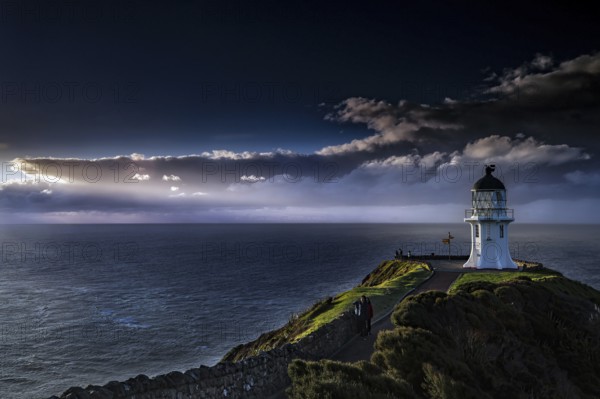Lighthouse under a dramatic sky lights up the sea at Cape Reinga, Cape Reinga, Northland, New