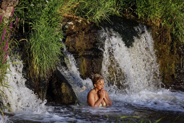 A woman enjoys water under Ventas Rumba waterfall in Kuldiga, Kuldiga, Latvia