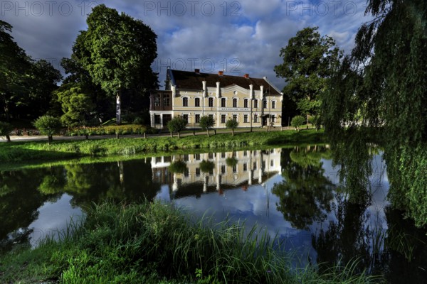 Kuldiga District Court with reflection in a quiet pond and surrounded by trees, Kuldiga, Courland,