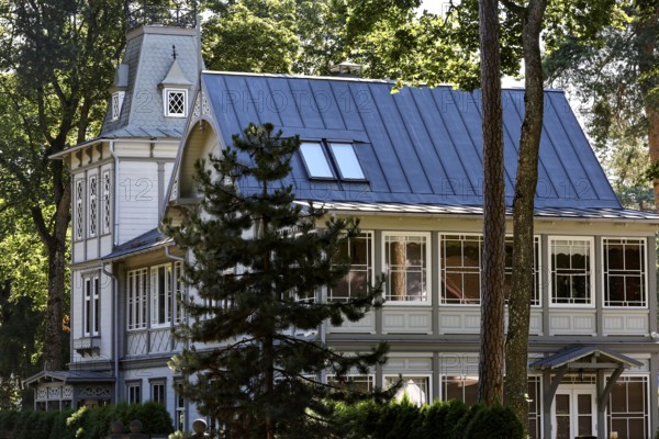 Elegant art nouveau wooden house with eye-catching blue roof under tall trees, Majori, Jurmala,