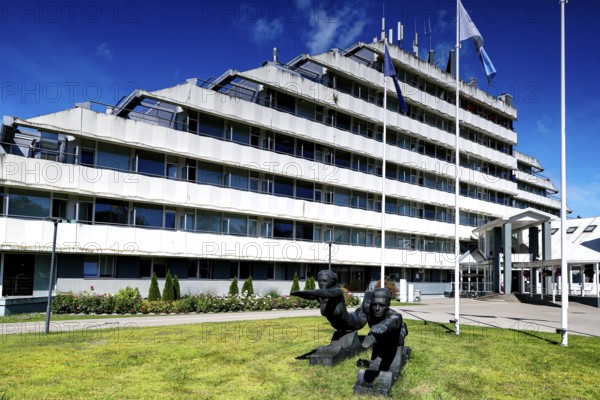 Modern sanatorium building with flags and well-kept green area against blue sky, Vaivari, Jurmala,