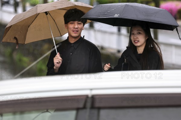 Smiling couple walking with umbrellas in the rain, Kurashiki, Okayama, Japan