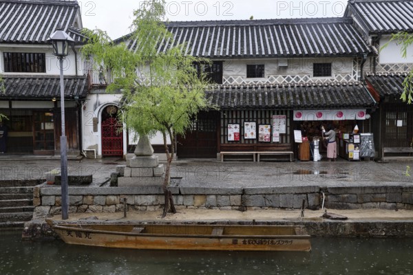 Traditional buildings along a canal in Kurashiki with a small boat in the foreground, Kurashiki,
