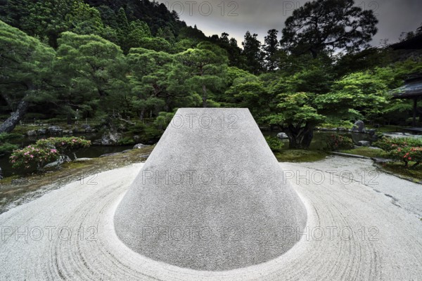 Zen garden with the cone-shaped sand hill Kogetsudai surrounded by green vegetation and trees,