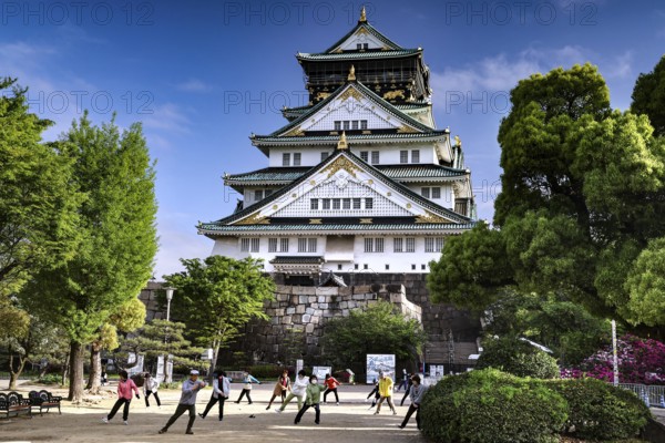 People practice tai chi in front of Osaka Castle, Osaka, Japan