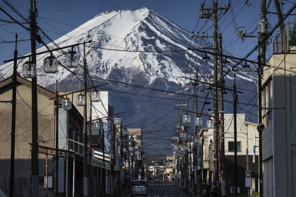 Majestic Fujiyama over a busy street in Fujioshida in golden morning light, Fujioshida, Japan