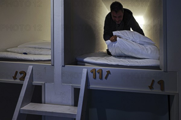 Man in sleeping capsule in a Japanese capsule hotel. Cozy and compact accommodation, Ise, Mie,