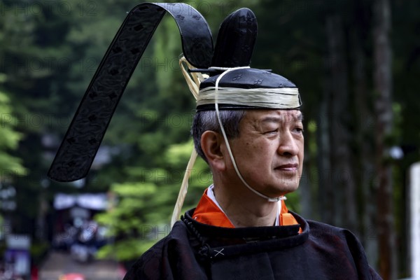 Man wearing traditional clothing and distinctive head covering during a cultural festival in Nikko,