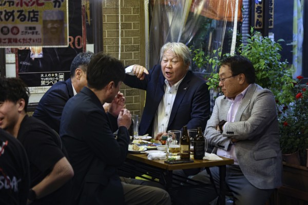 Men in suits talk vividly at a table in the Hoppy-dori, Tokyo, Tokyo, Japan