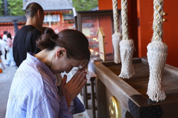 A woman prays reverently at Kumano Nachi Taisha Shrine, Seiganto-ji, with folded hands,
