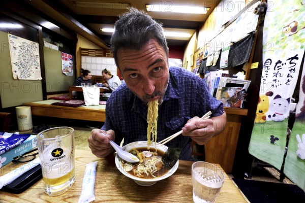 Man enjoying ramen in a cozy Japanese restaurant, Yamanouchi, Japan