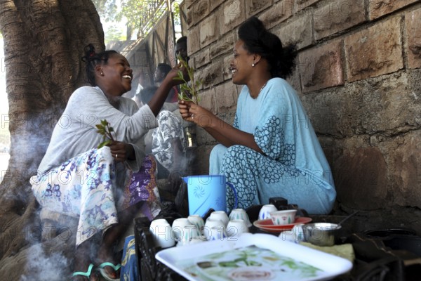 Two woman enjoy a traditional coffee ceremony and share moments of laughter, Asbe Teleri, Afar,
