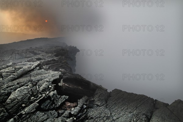 Smoke rises from a crater in a volcanic landscape, zero