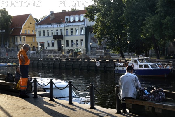 Anglers on the Dange in Klaipeda with a view of historic buildings and boats, Klaipeda, null,