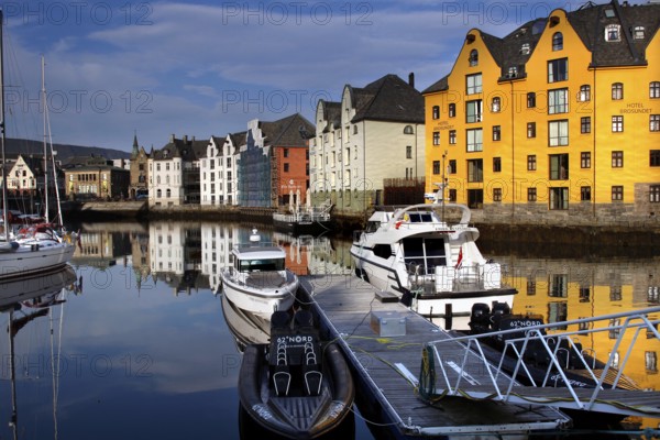 Colourful buildings and boats are reflected in the calm waters of Ålesund Harbour, Ålesund, Møre og